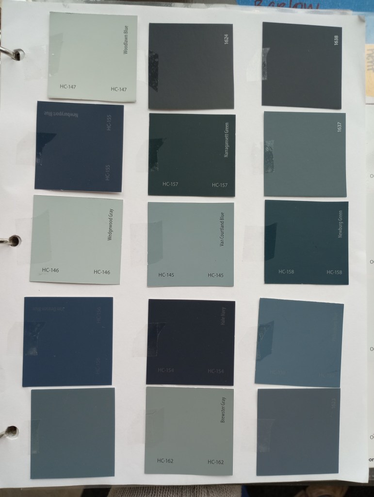 Blue benjamin moore color swatches taped to white piece of paper for exterior house. 